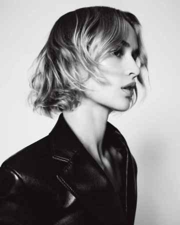 Model wearing a black leather jacket in profile against a bright white background