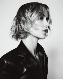 Model wearing a black leather jacket in profile against a bright white background