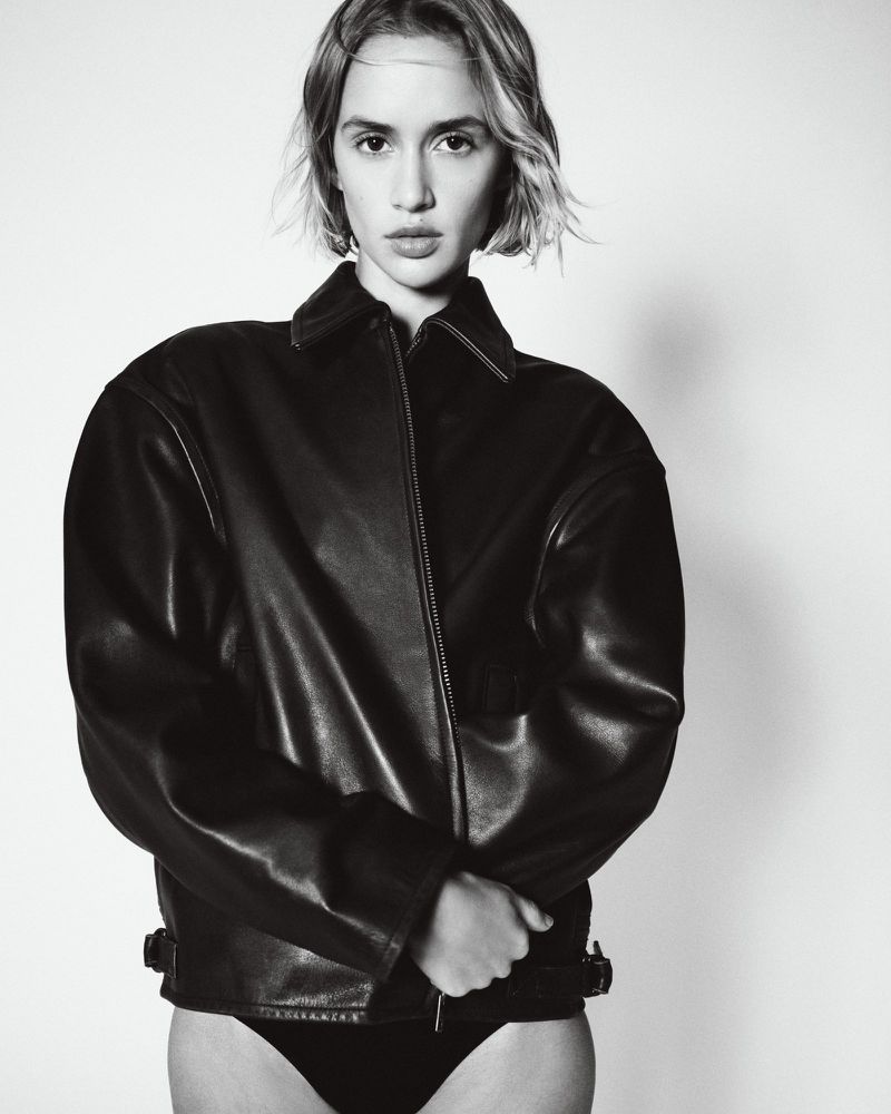 Model wearing a black leather jacket against a neutral studio background