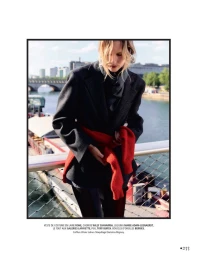 Model in dark blazer and red sweater standing on a bridge over a river for Madame Figaro editorial