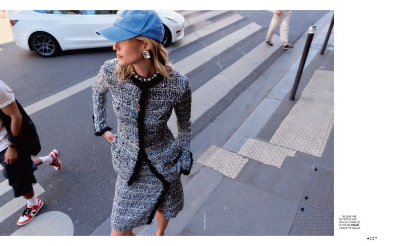 Model in tweed jacket and skirt wearing a blue baseball cap on a city street for Madame Figaro.