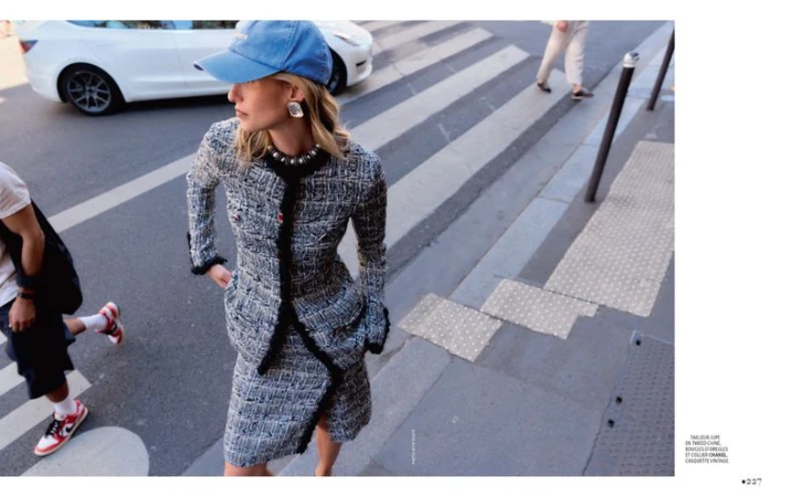 Model in tweed jacket and skirt wearing a blue baseball cap on a city street for Madame Figaro.