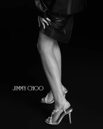 Close-up of a model wearing high-heeled sandals adorned with pearls against a dark background, Jimmy Choo Pearls of Wisdom campaign.