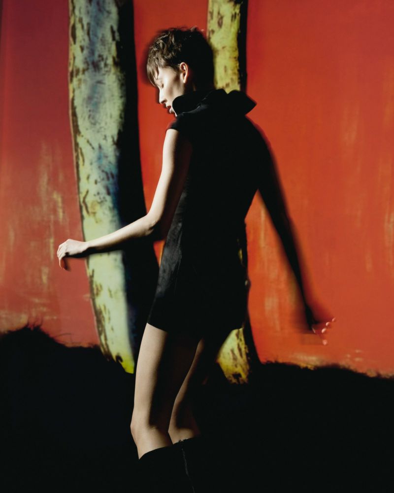 Model in a black dress standing against a vibrant red backdrop with textured columns for Vogue Portugal Dreamscape editorial