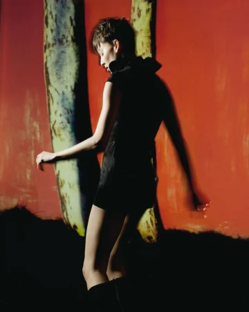 Model in a black dress standing against a vibrant red backdrop with textured columns for Vogue Portugal Dreamscape editorial