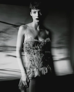 Monochrome fashion portrait of a short-haired woman wearing a textured strapless top against a blurred background.