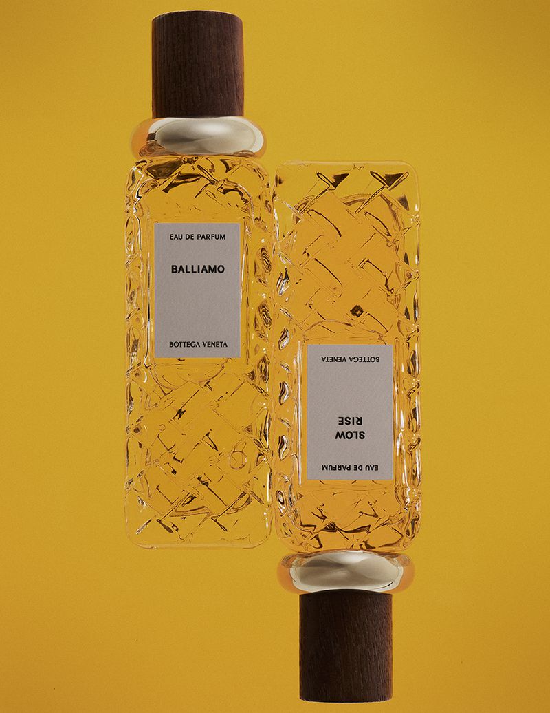 Two glass perfume bottles with textured patterns and wooden caps set against a vibrant yellow background