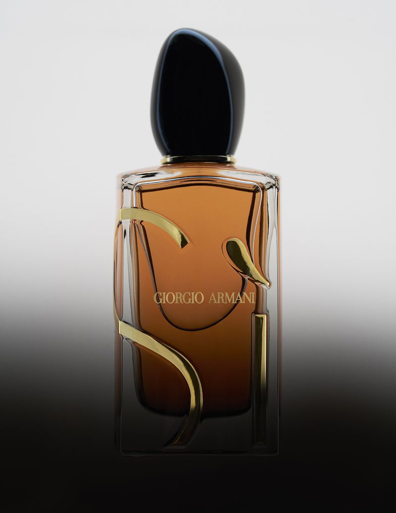 Giorgio Armani perfume bottle with amber liquid and gold lettering against a gradient studio background.