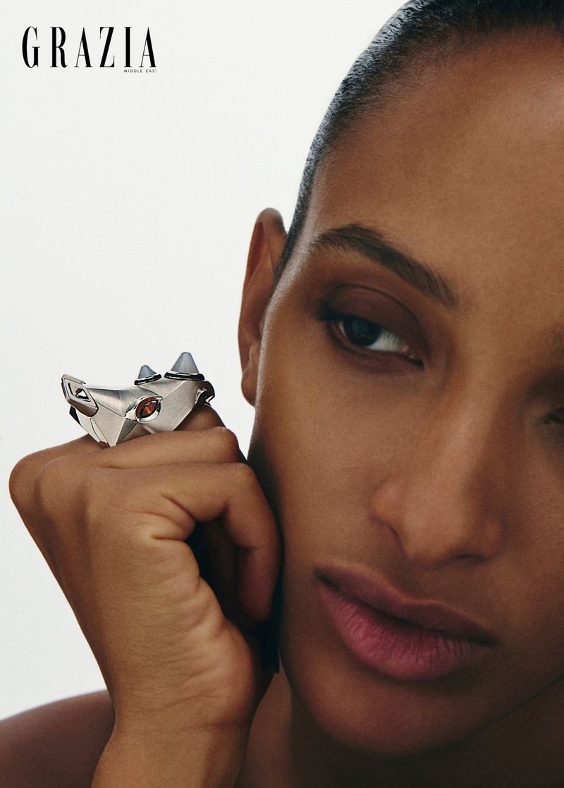 Close-up portrait of a woman wearing an animal-shaped silver statement ring against a white background.