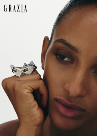 Close-up portrait of a woman wearing an animal-shaped silver statement ring against a white background.