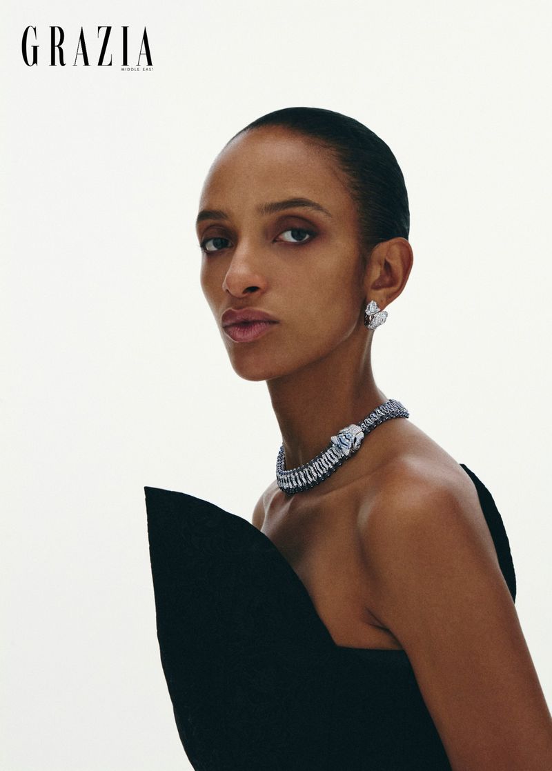 Model wearing a structured black dress and a diamond panther necklace against a plain white background for Grazia Middle East