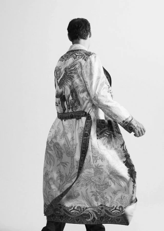 Model wearing a patterned long robe with a belted waist seen from behind against a plain white background