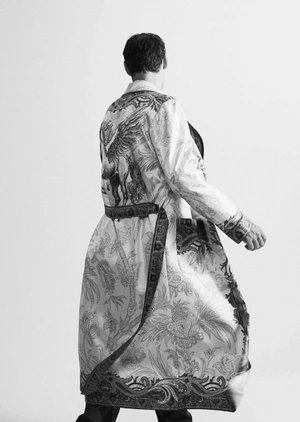 Model wearing a patterned long robe with a belted waist seen from behind against a plain white background