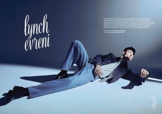 Male model in denim jeans and jacket lying on a smooth blue studio floor with cinematic lighting for GQ Turkey