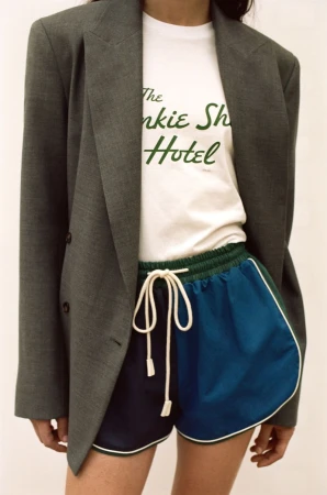 Model wearing a grey blazer over a white t-shirt and blue athletic shorts for The Frankie Shop SS27 lookbook.