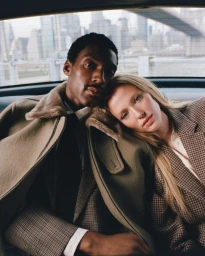 Halid Nuhu and Maelle Swaelens seated together in the back of a car with a city skyline visible through the window.