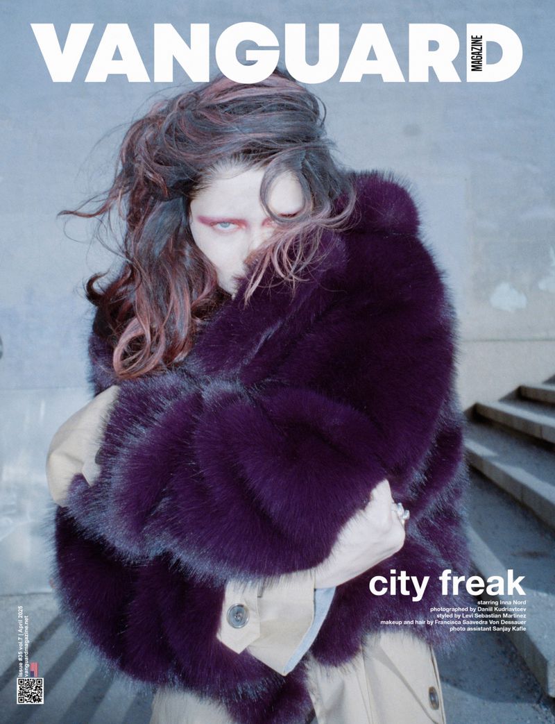 Magazine cover featuring model in fur coat with artistic makeup in an urban setting, promoting fashion and beauty.