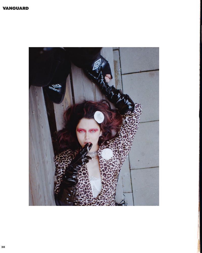 Woman in animal-print blazer poses with Umbro-branded clothing on a wood and stone surface, captured from a high angle.