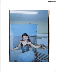 Model in a light blue tulle skirt and dark metallic top posing against industrial metal racks for Vanguard Magazine.