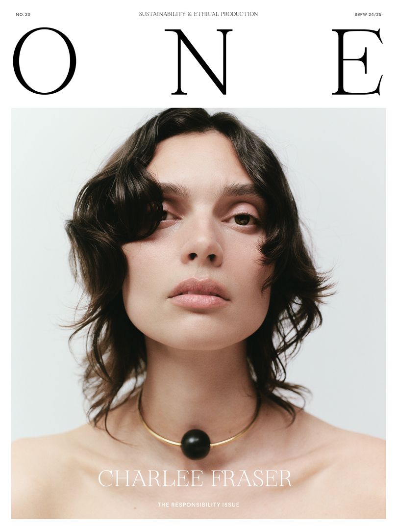 Magazine cover featuring a portrait of a young adult female with brown curly hair and a black ball necklace against a white background.