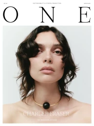 Portrait of a woman wearing a thin gold choker necklace with a large black spherical pendant against a plain white background.