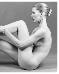 Iselin Steiro in profile wearing ornate dangling earrings against a neutral grey studio backdrop