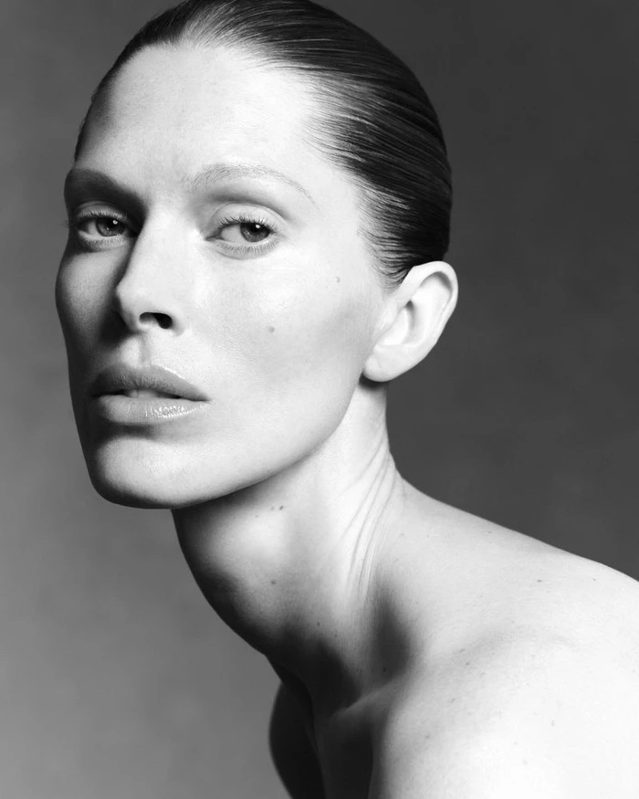 Close-up monochrome portrait of model Iselin Steiro with slicked-back hair against a dark background