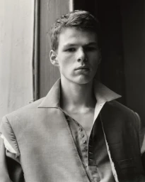 Portrait of a young man wearing a structured collared jacket in a monochrome photograph shot by Keith Oshiro.