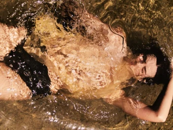 Model floating in shallow water with sunlight rippling across the surface for Cake Magazine photographed by Luke Lovell