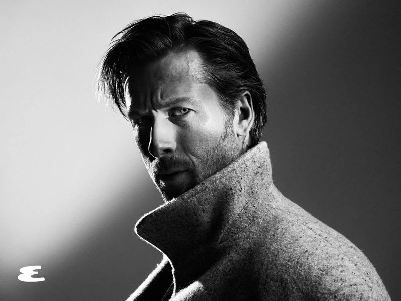 Portrait of Glen Powell wearing a textured high-collar coat in dramatic monochrome lighting for Esquire U.S.