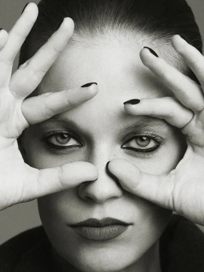 Close-up portrait of model Lexi Boling holding her hands up to frame her eyes, featuring dark nail polish and dramatic eye makeup for W Magazine China.