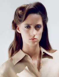 Portrait of a female model wearing a beige collared shirt against a white seamless background