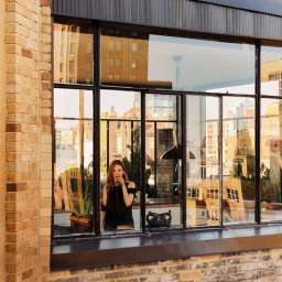 Julianne Moore standing inside a room with large glass windows reflecting city buildings for Architectural Digest