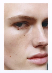 Extreme close up macro portrait of a person face focusing on the eye, nose, and lips with natural skin texture and freckles.