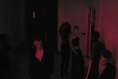 Group of models in dark clothing posing in a dimly lit red-toned indoor space for GQ Turkey 149 BPM editorial