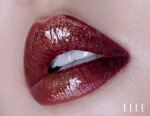 Close-up macro shot of glossy red and bronze lipstick on parted lips revealing white teeth for Elle China by Dalong Yang.