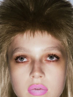 Close-up beauty portrait of a model with voluminous brown hair and bright pink lipstick for Elle Mexico.