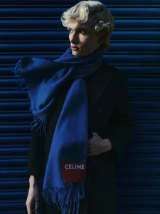 Blonde male model wearing a dark coat and a bright blue scarf for Manifesto Magazine