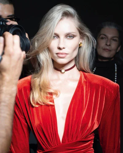 Model Vika Falileeva wearing a red velvet v-neck dress and choker necklace backstage for Citizen K International