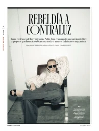 Magazine page layout featuring a model wearing dark sunglasses, white lace top, and grey trousers seated in a chair against a white background.