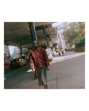 Model Aweng Chuol walking on a city sidewalk beneath an elevated roadway for Heroine Magazine.