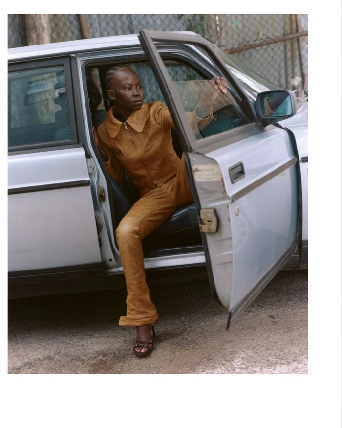 Aweng Chuol in a brown leather outfit exiting a silver car for Heroine Magazine