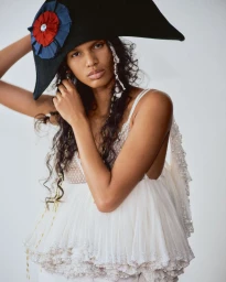 Model Achol Ayor wearing a large tricorn hat and white sheer tiered top for Family Style, captured by Will Scarborough.