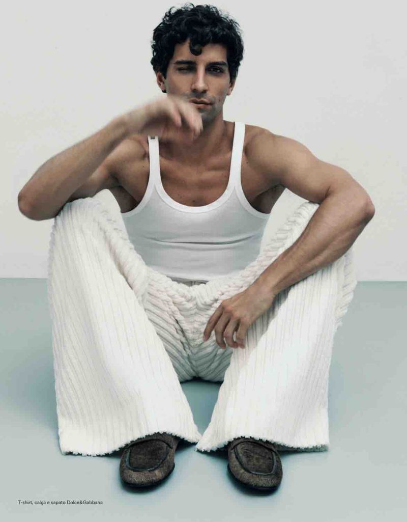 Model Francisco Faria seated on the floor wearing a white tank top and textured white trousers photographed by Guilherme da Silva