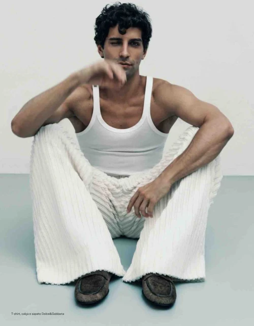 Model Francisco Faria seated on the floor wearing a white tank top and textured white trousers photographed by Guilherme da Silva
