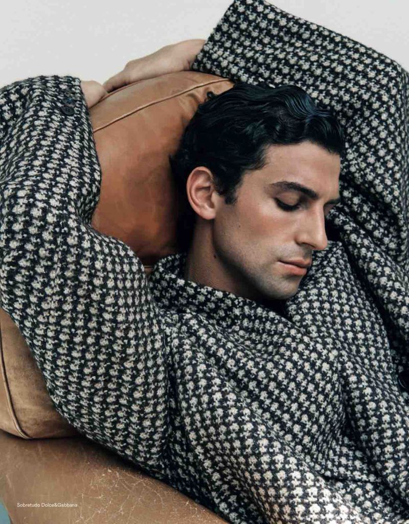 Close-up portrait of a male model in a patterned black and white jacket leaning against a leather headrest