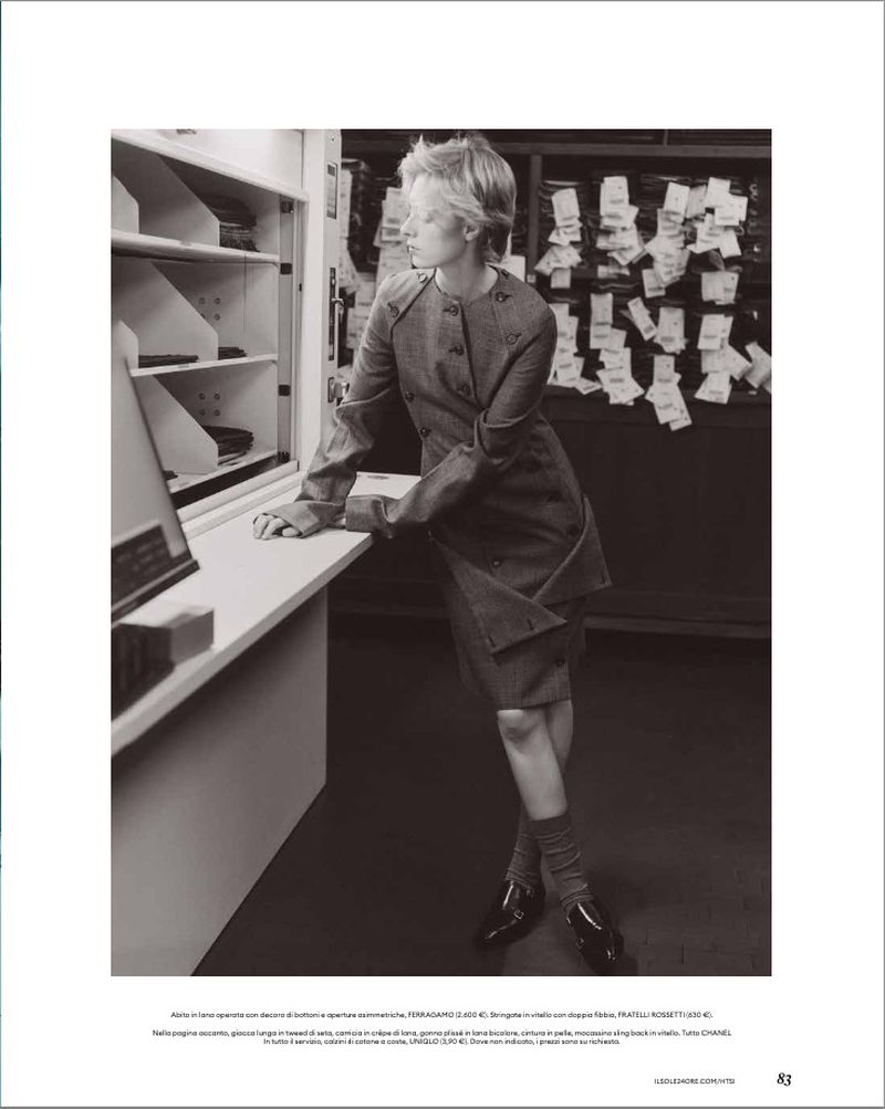 Monochrome fashion editorial image of a woman leaning against a counter in an archive or library setting.