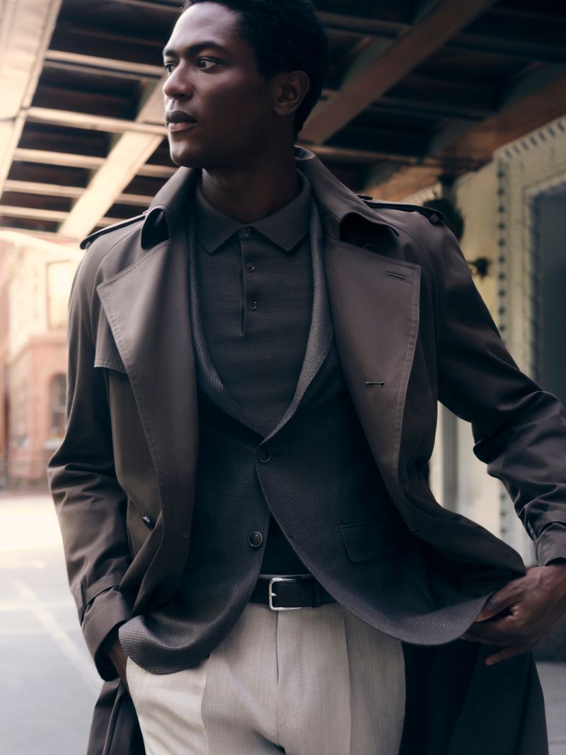 Model Hamid Onifade in a BOSS trench coat and polo shirt on an urban street for A Life In The City campaign.