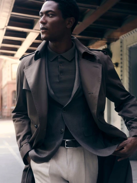 Model Hamid Onifade in a BOSS trench coat and polo shirt on an urban street for A Life In The City campaign.