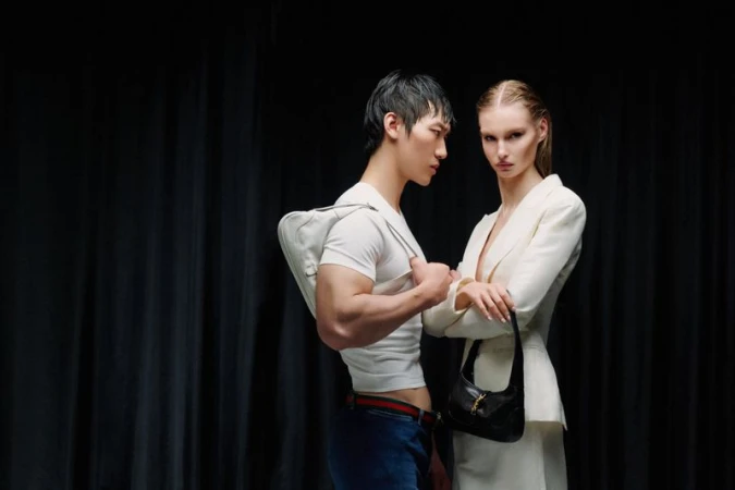 Man and woman posing against dark drapes for L Officiel Chile Spirito Audace editorial by Fabian Agustin